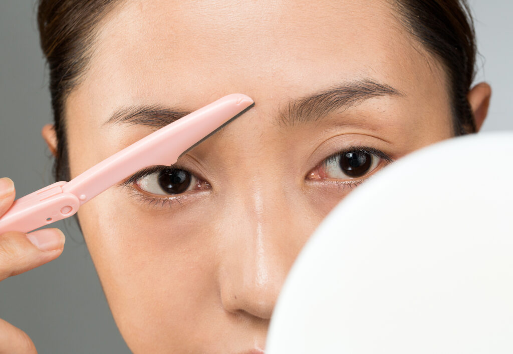 眉間をシェービングしている女性